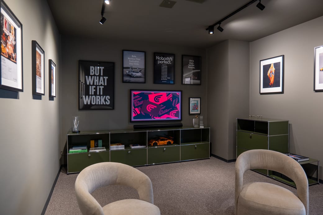 Kundenlounge von Curved Culture mit Sesseln, Bildschirm und Bildern an der Wand